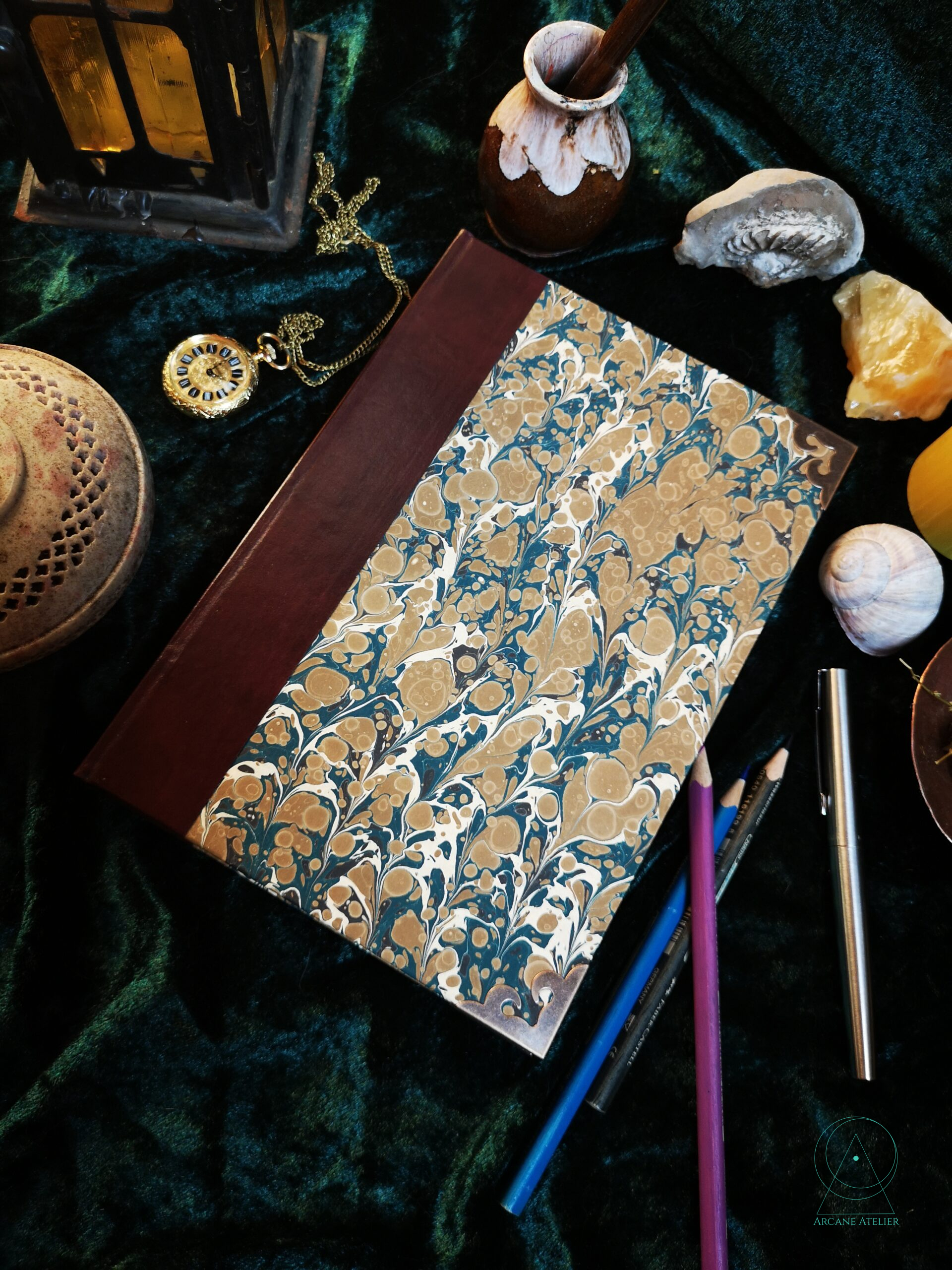 Franzband-style journal with a dark red leatherette spine and brown-blue-white traditional marbled paper covers.