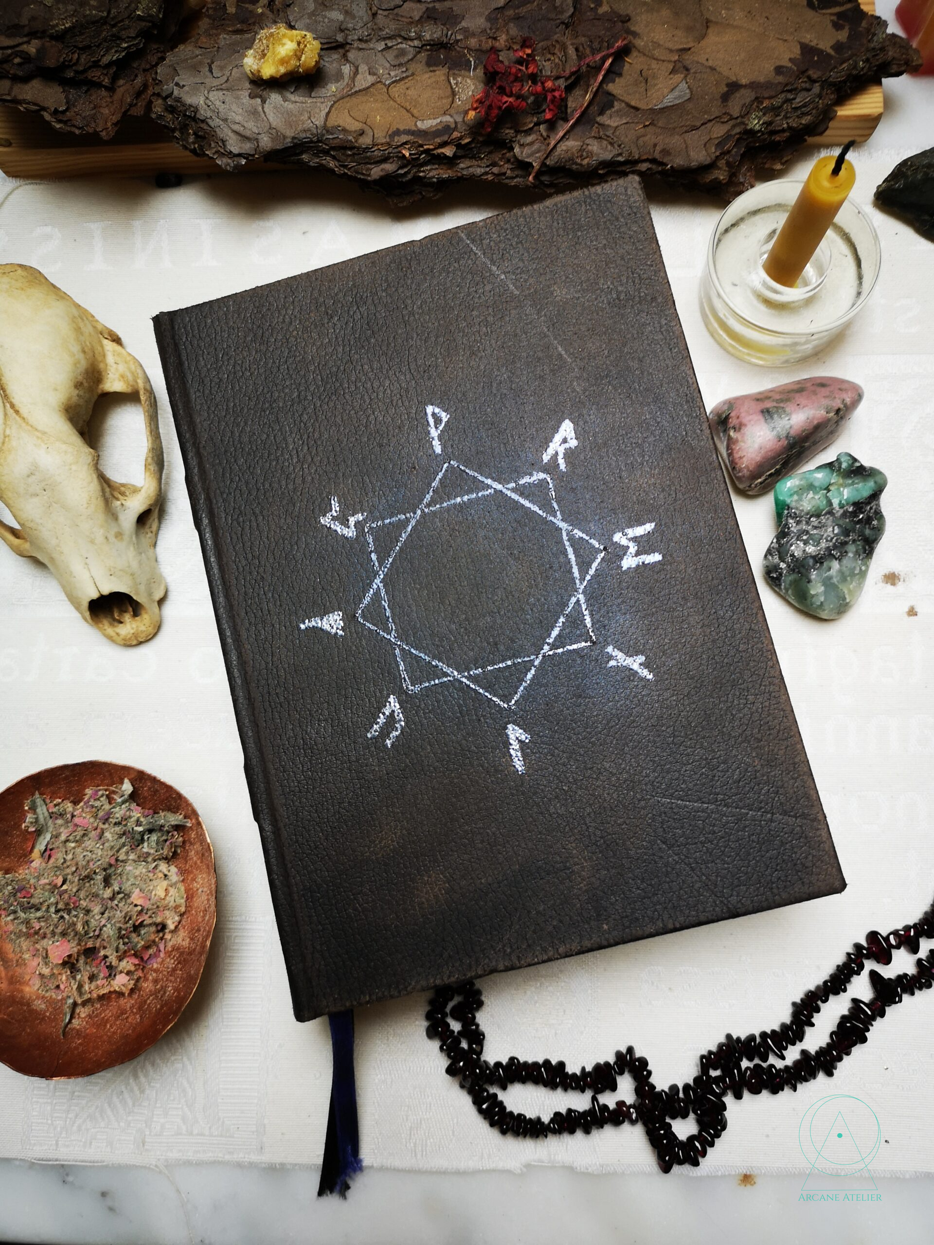 Brown aged-leather journal with four interlocking corner ornaments forming an eight-pointed star and a silver rune circle.