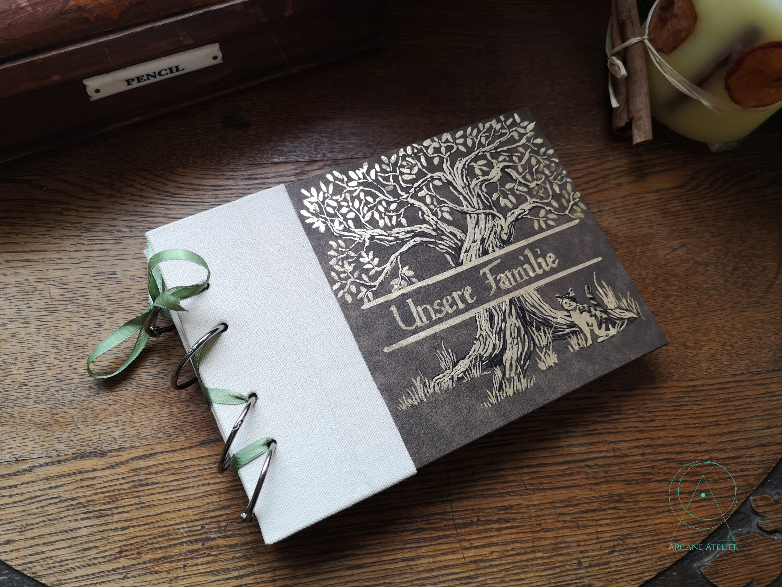 Family tree record book with two-thirds brown leatherette and a natural linen spine, ring-bound with a light green ribbon.