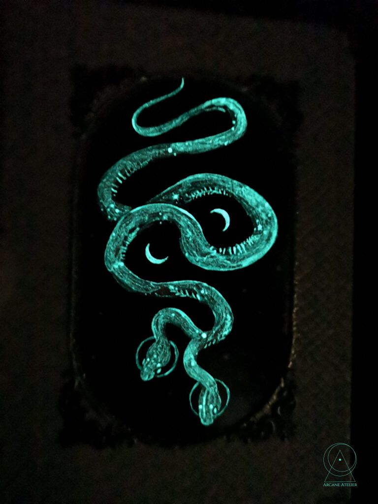 Night shot of the Serpent Skin Journal showing the softly glowing snake artwork.
